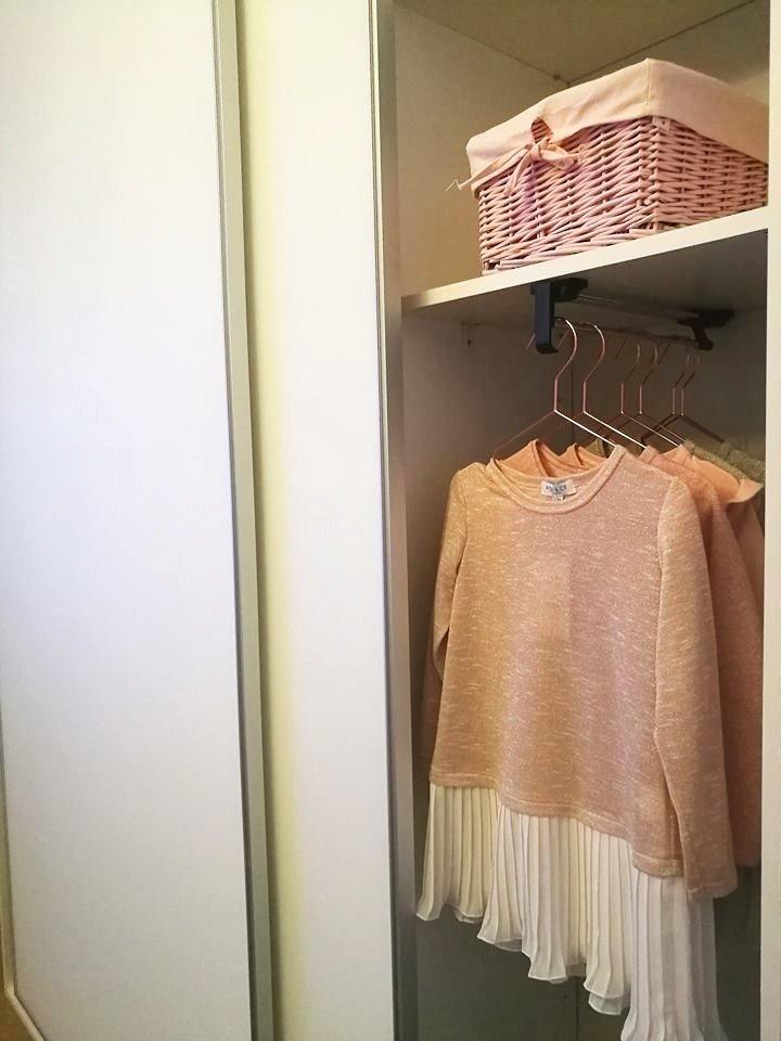 Liukuovikaapiston sisältö, jossa on hyllytilaa ja vaatetanko, johon on ripustettu mekkoja.