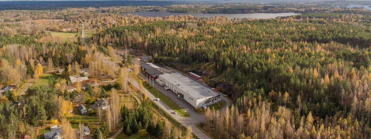 Ilmakuvassa kotimaisen liukuovituotannon tehdas Pälkäneellä suomalaisen metsän keskellä.